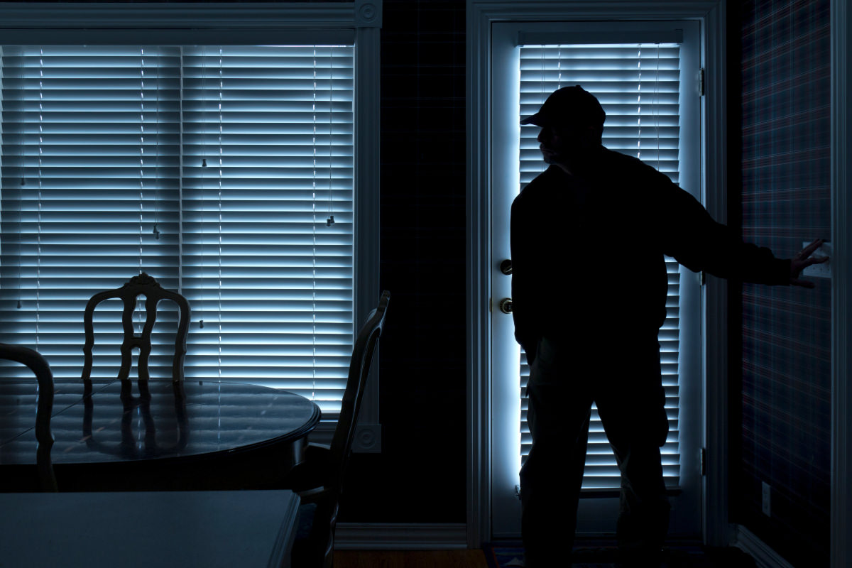 Silhouette d'un intrus entrant dans une maison la nuit